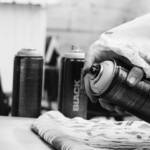 Image en noir et blanc. Une main tient une bombe de spray et peint.